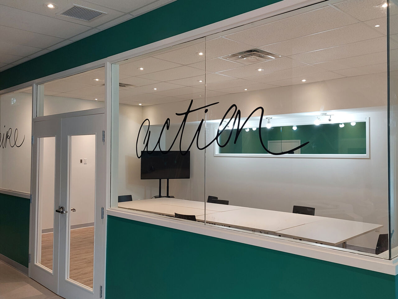 Salle de réunion vitrée avec inscription « action » et mobilier de formation, Centre communautaire de Bromont