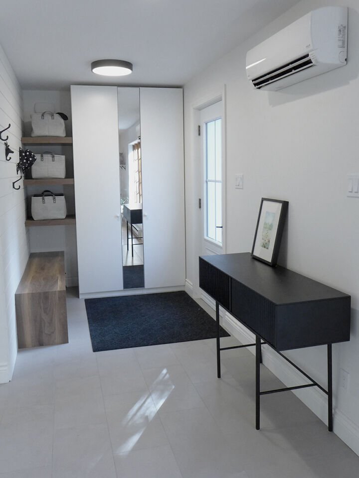 Entrée rénovée avec meuble console noir, plancher restauré et nouvel éclairage, Maison du Ruisseau rouge à Magog
