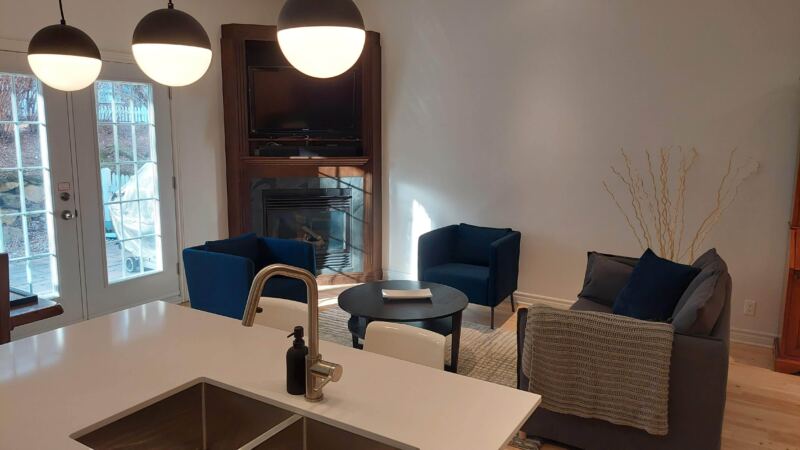 Salon avec foyer encastré, fauteuils bleu marine et table basse noire, Résidence Verdet