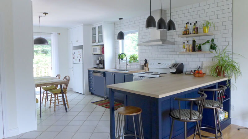 Cuisine rénovée avec comptoir "bar" côté salon, nouvel îlot et dosseret de carreaux blancs, projet Audrée à Bromont